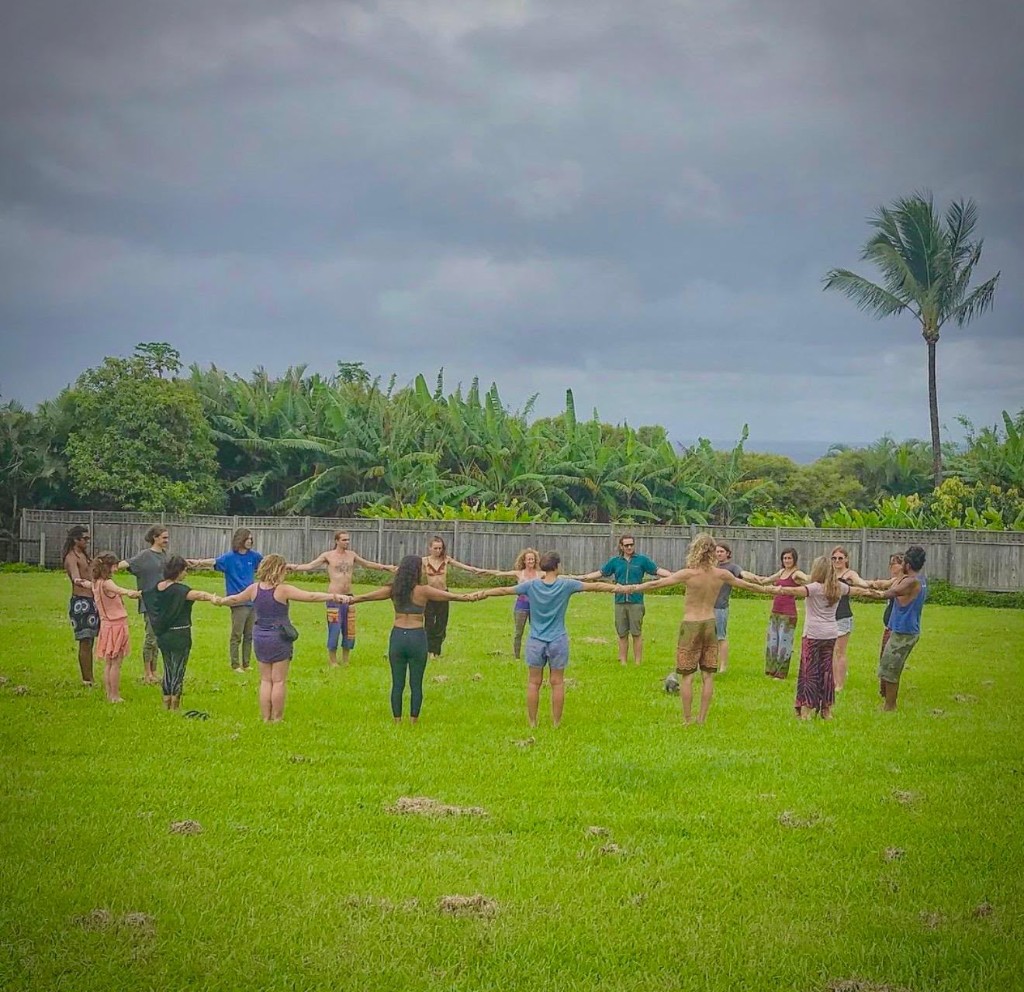Community circle holding hands on a green lawn